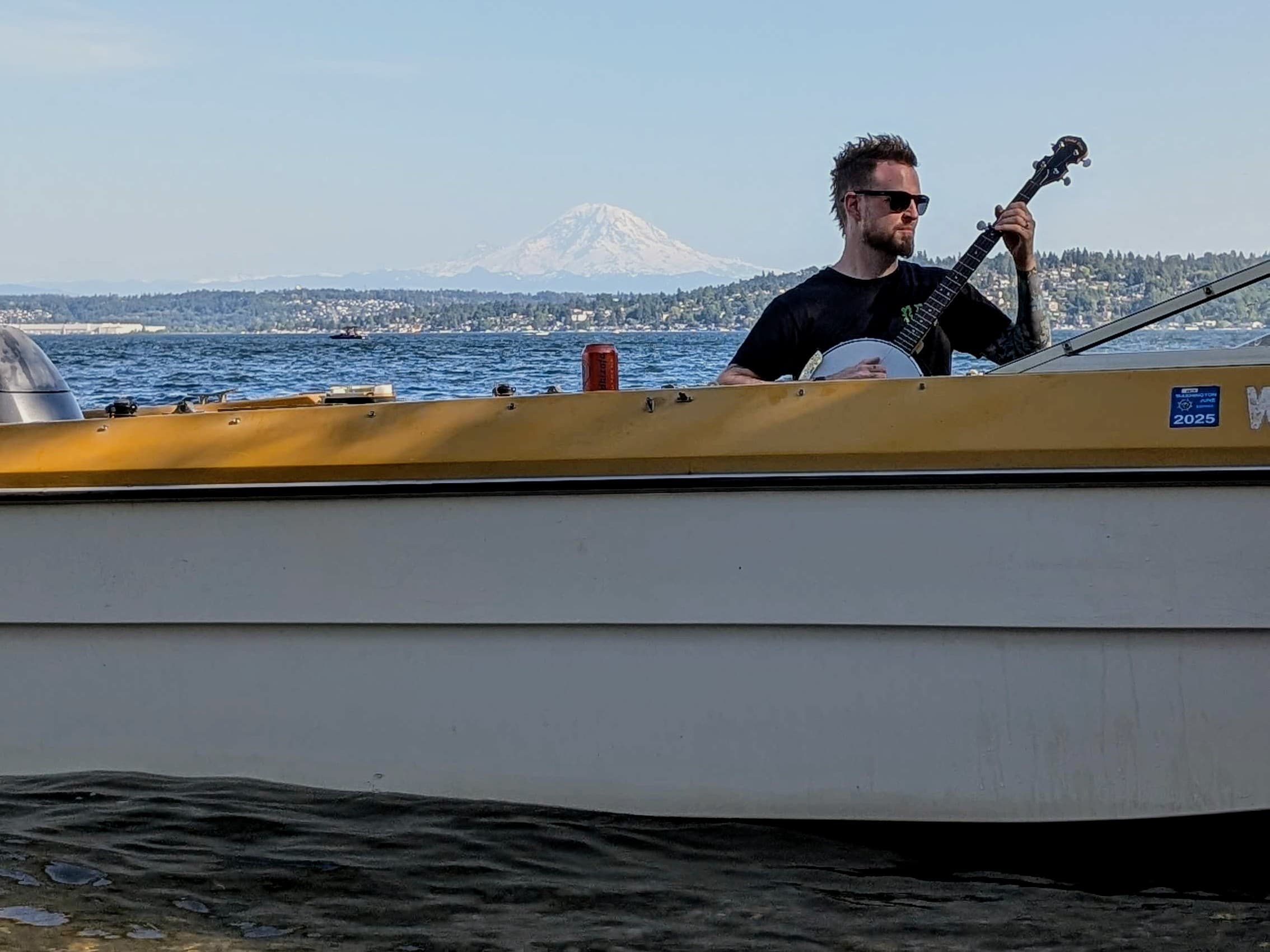 me on a small boat playing banjo with Mt Rainier behind me